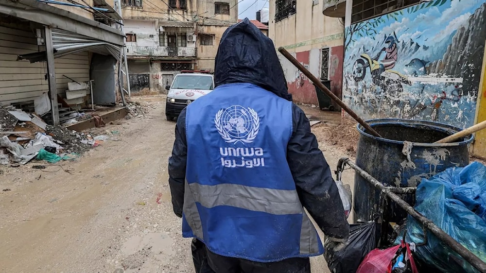 An UNRWA worker in Jenin collects rubbish from the streets of a refugee camp, January 30, 2024. (AFP)