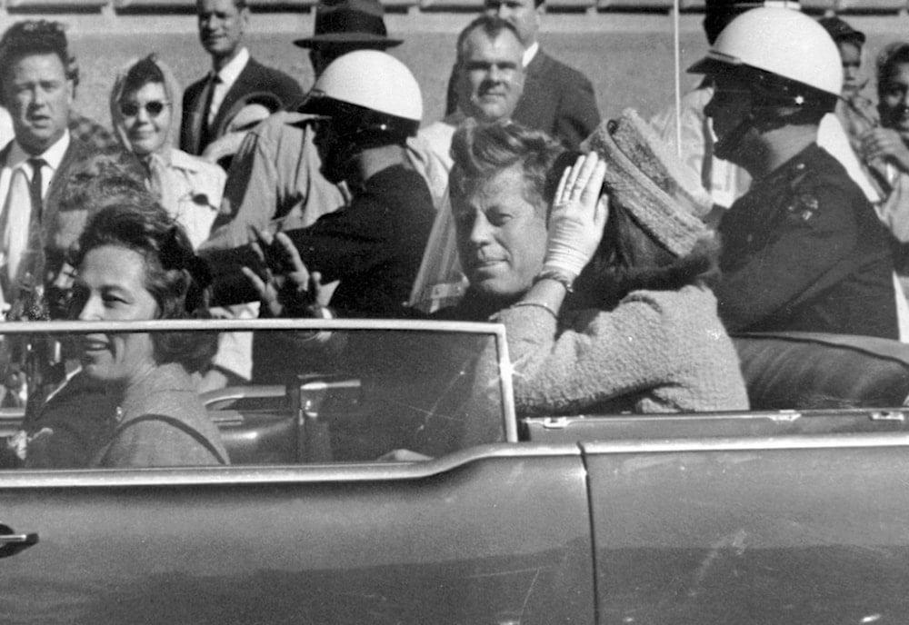 President John F. Kennedy waves from his car in a motorcade approximately one minute before he was shot, Nov. 22, 1963, in Dallas (AP)