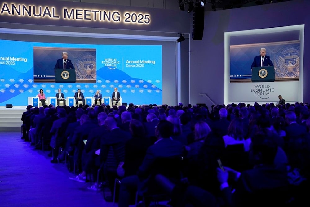 People follow a virtual speech of U.S. president Donald Trump at the Annual Meeting of World Economic Forum in Davos, Switzerland, Thursday, Jan. 23, 2025. (AP Photo/Markus Schreiber)