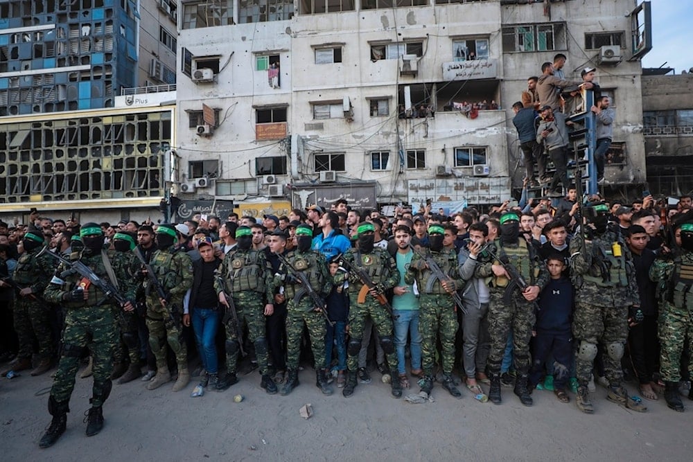 Fighters from the al-Qassam Brigades, the military wing of Hamas, control the crowd while Red Cross vehicles come to collect Israeli captives to be released under a ceasefire agreement, in Gaza City, January 19, 2025 (AP)