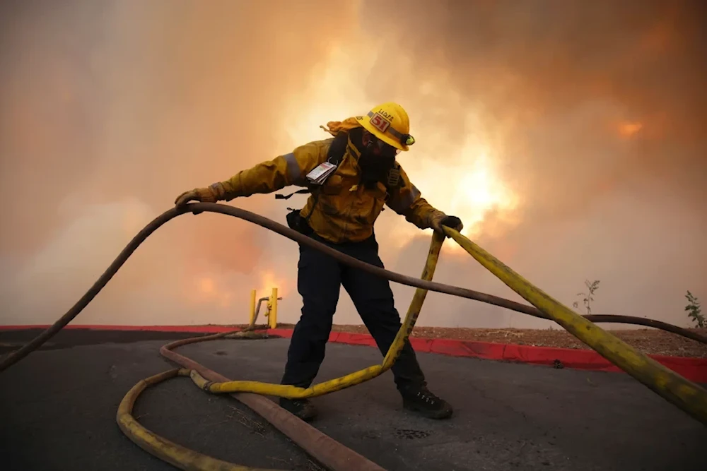 A firefighter sets out fire hoses to fight the Hughes Fire. (AP)