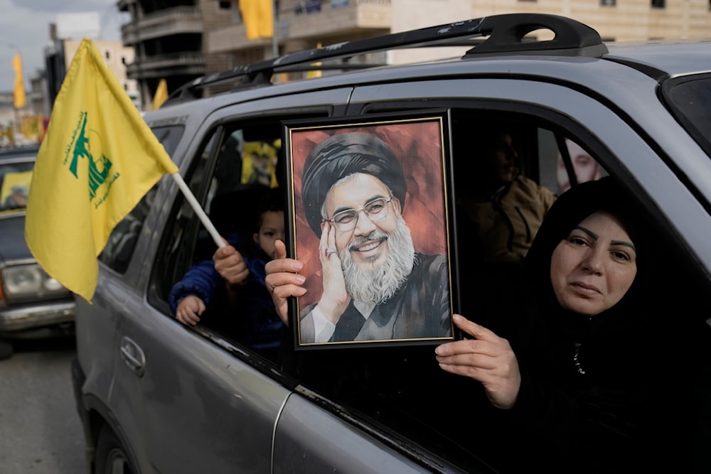 A Lebanese woman holds a portrait of martyred Hezbollah leader Sayyed Hassan Nasrallah, as she sits in a car with her family on their way to check their village in Bint Jbeil town, south Lebanon, Sunday, Jan. 26, 2025 (AP)