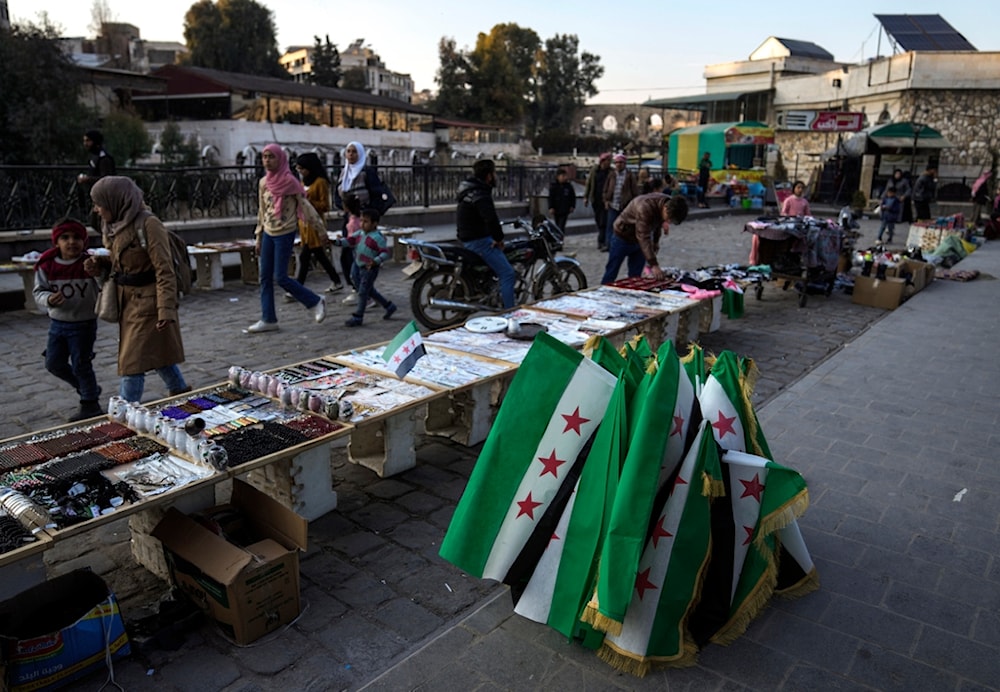 People pass by street vendors displaying goods for sale in the main square of Hama, Syria, Sunday, Jan. 26, 2025. (AP Photo/Khalil Hamra)