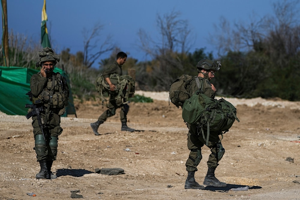 Israeli soldiers carry combat equipment as they return from the Gaza Strip at the separation line with Gaza, Saturday, Jan. 18, 2025. (AP Photo/Tsafrir Abayov)