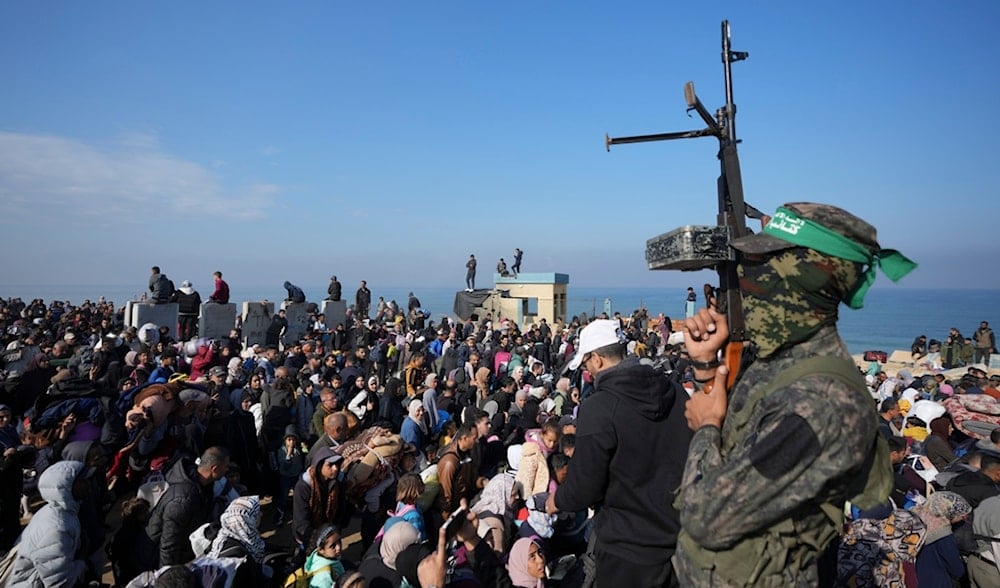 A Hamas fighter lifts his weapon as displaced Palestinians return to their homes in the northern Gaza Strip, Monday, Jan. 27, 2025 (AP)