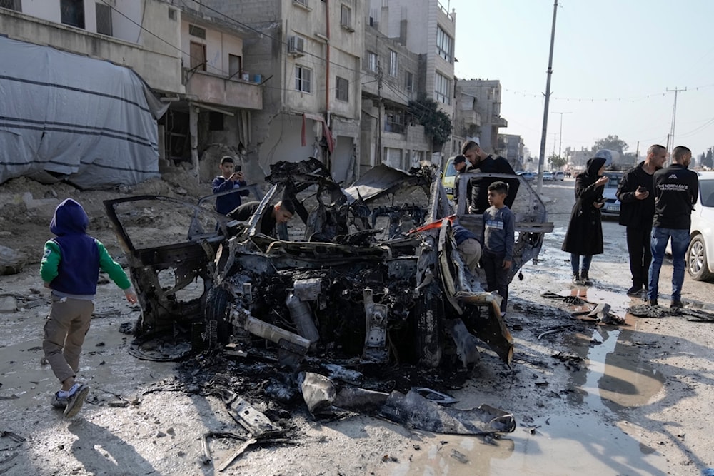 People view wreckage of a vehicle destroyed in an Israeli strike that killed two people in the West Bank refugee camp of Nur Shams, Tulkarem, Monday, Jan. 27, 2025 (AP)