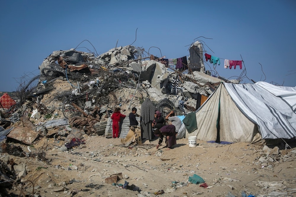 A Palestinian family sits outside a tent next to their destroyed house in Beit Lahia, northern Gaza Strip, Wednesday, Jan. 29, 2025. (AP)