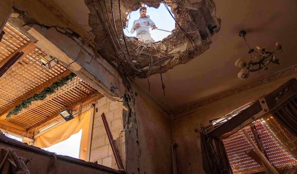 A man works on the roof of an apartment building struck by projectiles fired from Lebanon, in northwest occupied Palestine, Saturday, Nov. 9, 2024. (AP)