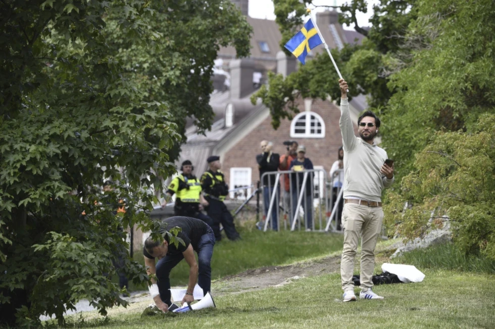 Protestor Salwan Momika waves the Swedish flag outside the Iraqi embassy in Stockholm, where he planned to burn a copy of the Quran and the Iraqi Flag on July 20, 2023. (AP)