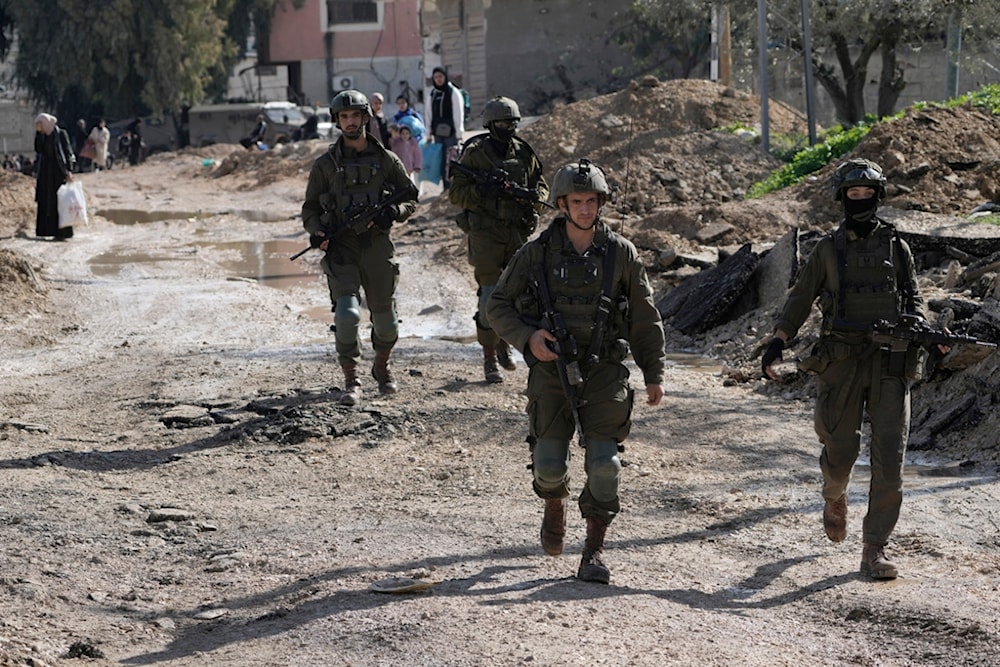 Israeli soldiers walk ahead of Palestinians displaced by an Israeli military operation to evacuate the Jenin refugee camp in the West Bank carrying their belongings on Thursday, Jan. 23, 2025 (AP)