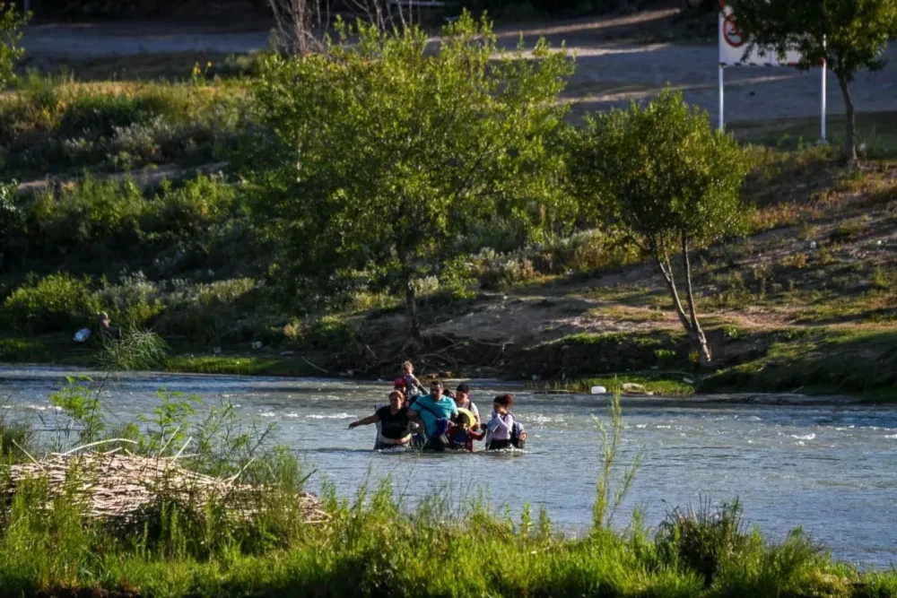 A migrant family from Venezuela crosses the Rio Grande river in Eagle Pass, Texas, at the U.S.-Mexico border on June 30. (AFP via Getty Images)