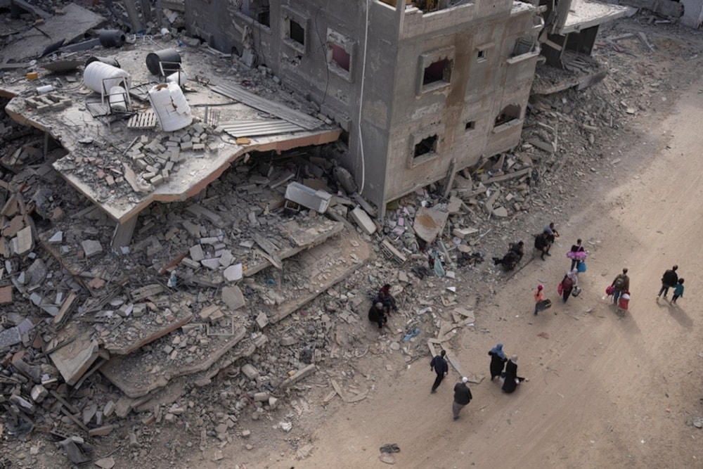 Palestinians walk through the destruction in the wake of an Israeli air and ground offensive in Khan Younis, southern Gaza Strip, on Monday April, 2024 (AP)