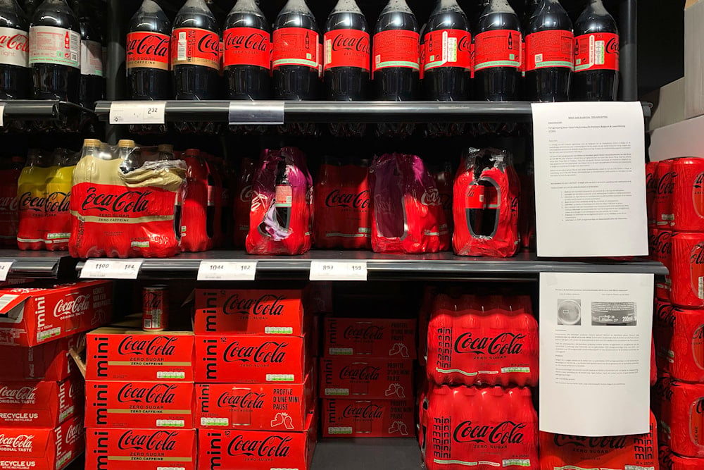 A note is posted next to cleared cases of soft drinks sitting on a shelf in a supermarket in Antwerp, Belgium, after Coca-Cola recalled some of its soft drinks in Europe, on January 28, 2025. (AP)