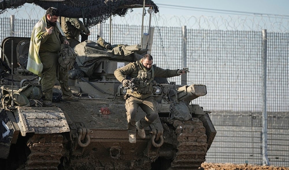 An Israeli soldier jumps off an armoured vehicle at a staging area near the Gaza border in southern 