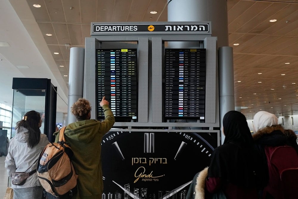 Travelers check departing flights at Ben Gurion International Airport near Tel Aviv, occupied Palestine, Tuesday, Dec. 31, 2024. (AP Photo/Matias Delacroix)