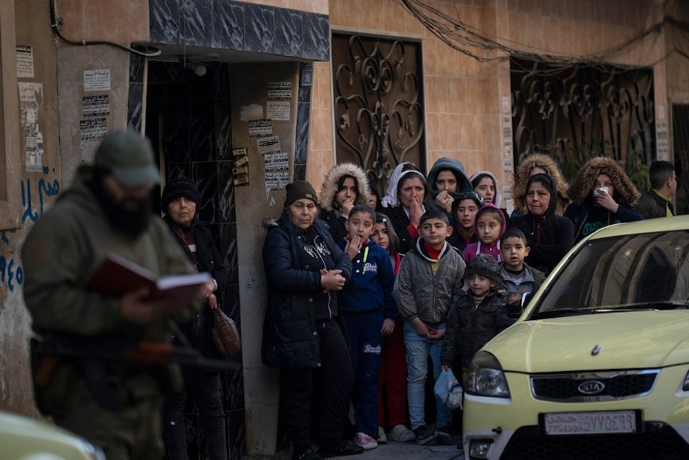 People stand outside their homes as members of the new security forces take part in an operation to detain men suspected of being part of militias or Syrian Arab Army soldiers in Homs, Syria, Friday, January 3, 2025 (AP)