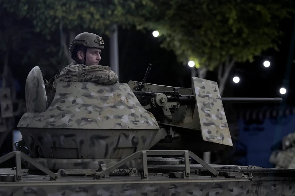 A Lebanese army soldier sits behind his weapon on the top of an armored personal carrier at the site of an Israeli airstrike in Beirut’s southern suburb, Monday September 23, 2024. (AP)