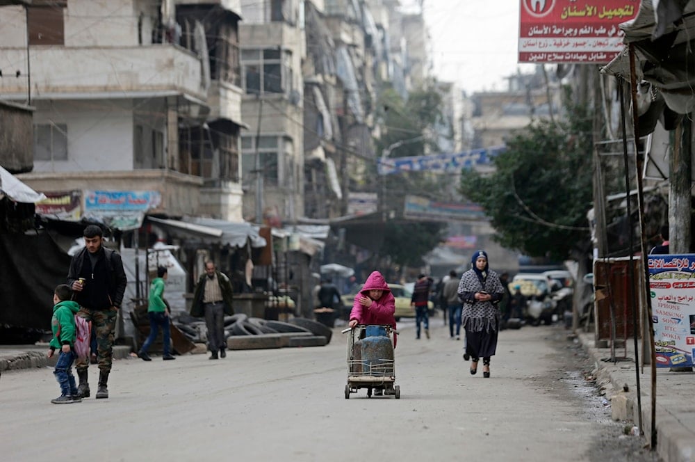 a Syrian girl pushes a cart loaded with cooking gas canisters, in Aleppo, Syria on December 5, 2016. (AP)