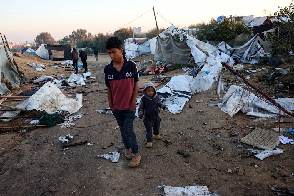 Palestinian children walk amid scattered debris of tents on January 2, 2025, following an overnight Israeli strike on a tent camp near Khan Younis in the southern Gaza Strip. (AFP)