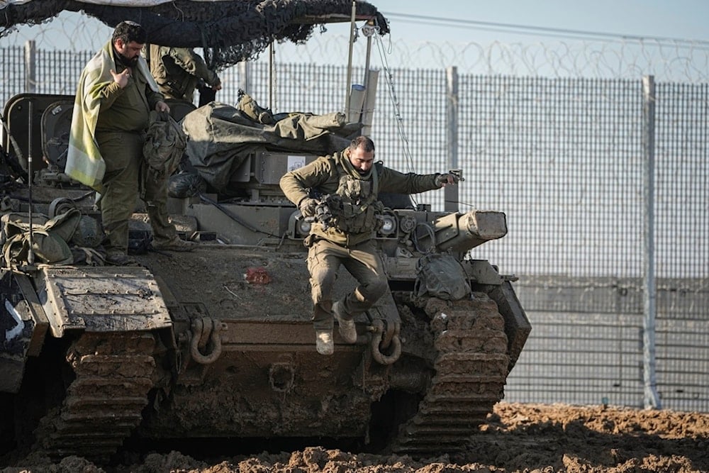 An Israeli soldier jumps off an armored vehicle at a staging area near the Gaza border in southern occupied Palestine, Thursday January 2, 2025 (AP)