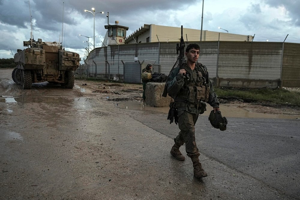 An Israeli soldier walks through a staging area as his unit prepares to enter the Gaza Strip at the Gaza border in southern occupied Palestine on Tuesday, Dec. 31, 2024 (AP)