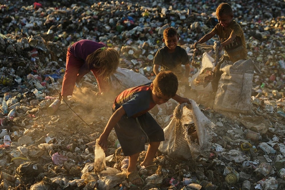 Displaced Palestinian children search for firewood and plastic in a landfill beside the makeshift tent camp where they are taking shelter, in Khan Younis, southern Gaza Strip, Tuesday, September 30, 2025. (AP Photo/Jehad Alshrafi)