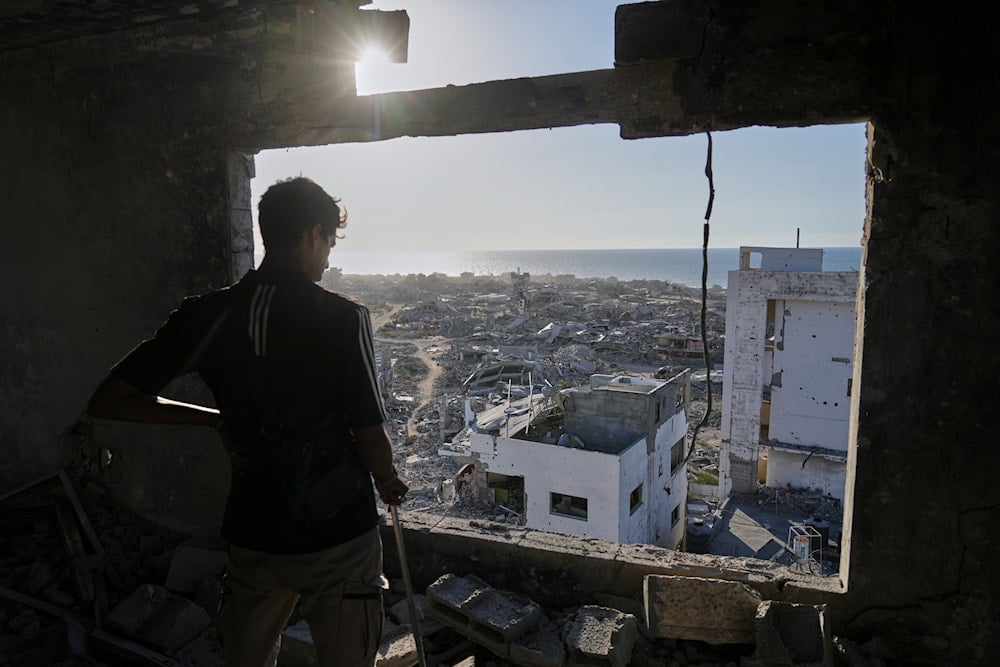 A man looks out from his damaged apartment at the destruction in his neighborhood in Gaza City, Friday, Oct. 10, 2025 (AP)