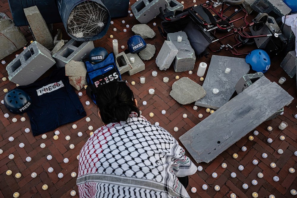 A demonstrator places electric candles among props ahead of a vigil honoring journalists killed by recent Israeli strikes in Gaza at Columbus Plaza near Union Station, Wednesday, Aug. 27, 2025, in Washington. (AP)