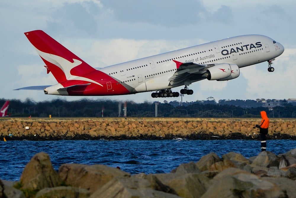A Qantas A380 takes off from Sydney Airport over Botany Bay as a fisherman stands on breakwater in Sydney, Australia, Monday, Sept. 5, 2022 (AP)