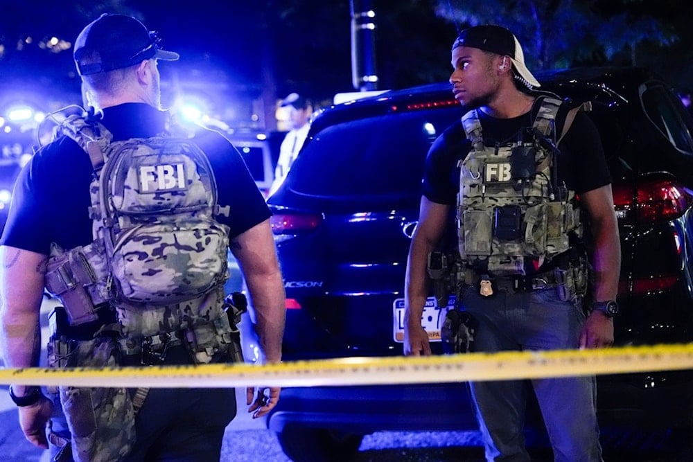 FBI agents stand behind a police line, Friday, August 22, 2025, on H Street in northeast Washington. (AP Photo/Julia Demaree Nikhinson)
