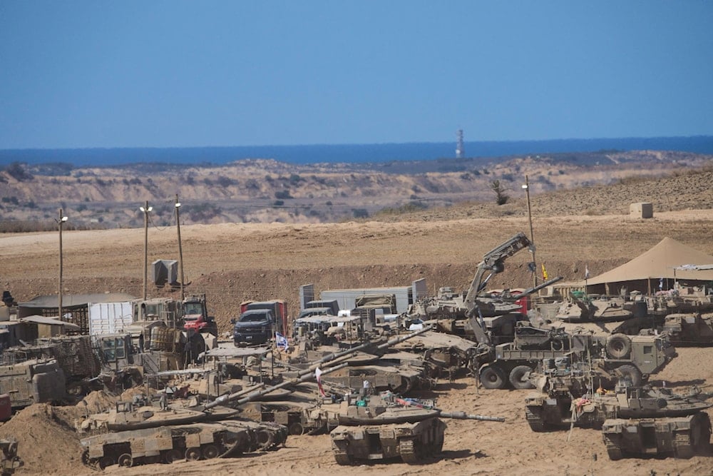Israeli soldiers work on their tanks at a gathering point on the border with the Gaza Strip, in Occupied Palestine, Saturday, Oct. 11, 2025 (AP)