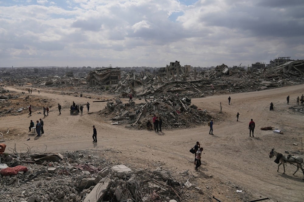 Displaced Palestinians walk amid destroyed buildings in al-Jalaa Street in Gaza City, Sunday, October 12, 2025 (AP)