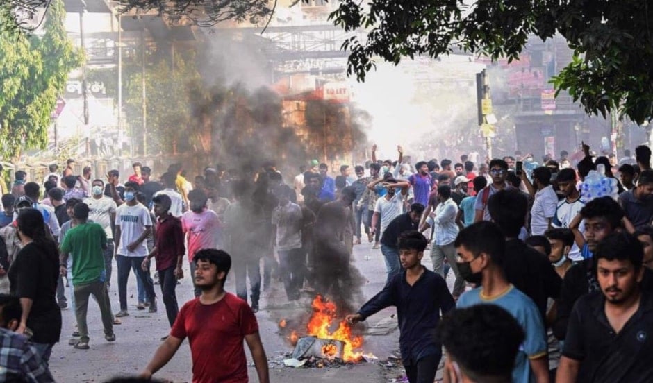 Protesters wave national flags as they stand over the Anti Terrorism Raju Memorial Sculpture during a protest in Dhaka on August 4, 2024. (AFP)