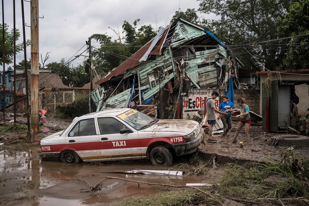 Neighbors gather around a damaged house after heavy rainfall in Poza Rica, Veracruz state, Mexico, Saturday, Oct. 11, 2025. (AP Photo/Felix Marquez)