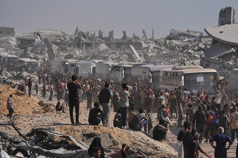 Buses carrying freed Palestinian prisoners drive past destroyed buildings in the Gaza Strip, in Khan Younis, southern Gaza Strip, Monday, October 13, 2025 (AP)