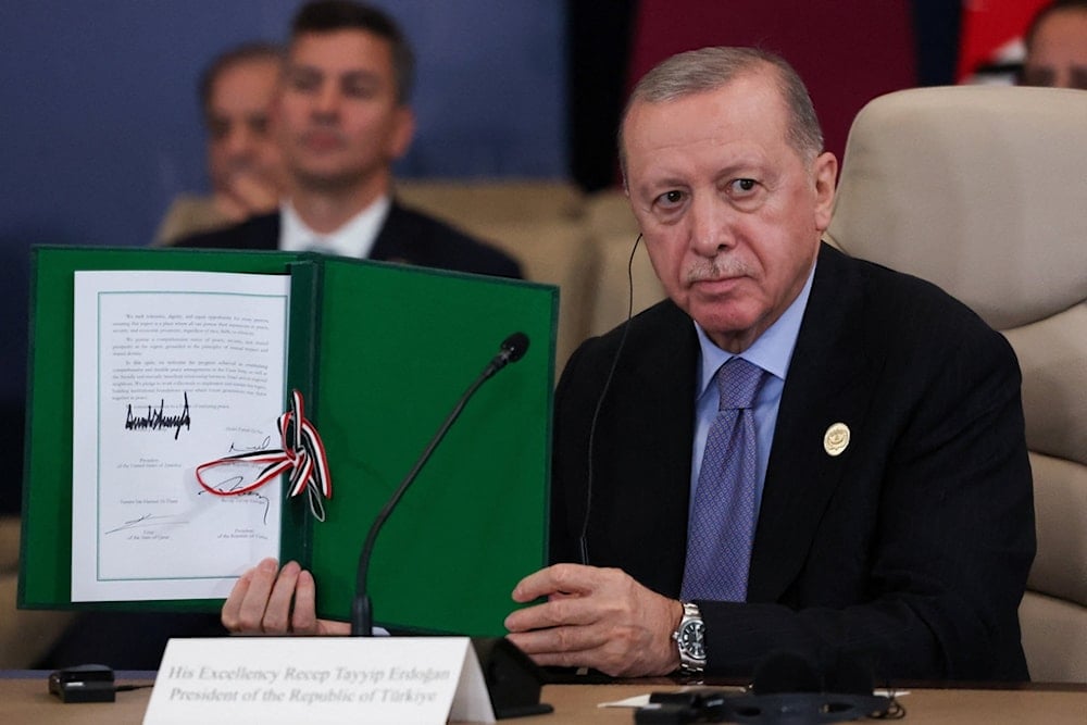 Turkey's President Recep Tayyip Erdogan holds a signed document during a summit to support ending the more than two-year war on Gaza
