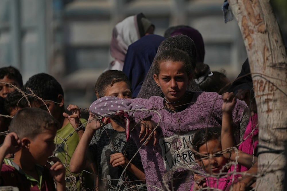 People gather at the site where Israeli captives are to be handed over by Hamas to the Red Cross, in Khan Younis, southern Gaza Strip, Monday, October 13, 2025 (AP)