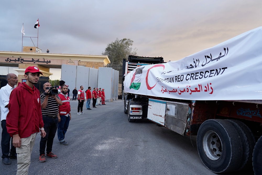 Egyptian Red Crecent members monitor trucks carrying humanitarian aid as they enter the Rafah crossing between Egypt and the Gaza Strip, October 12, 2025 (AP)