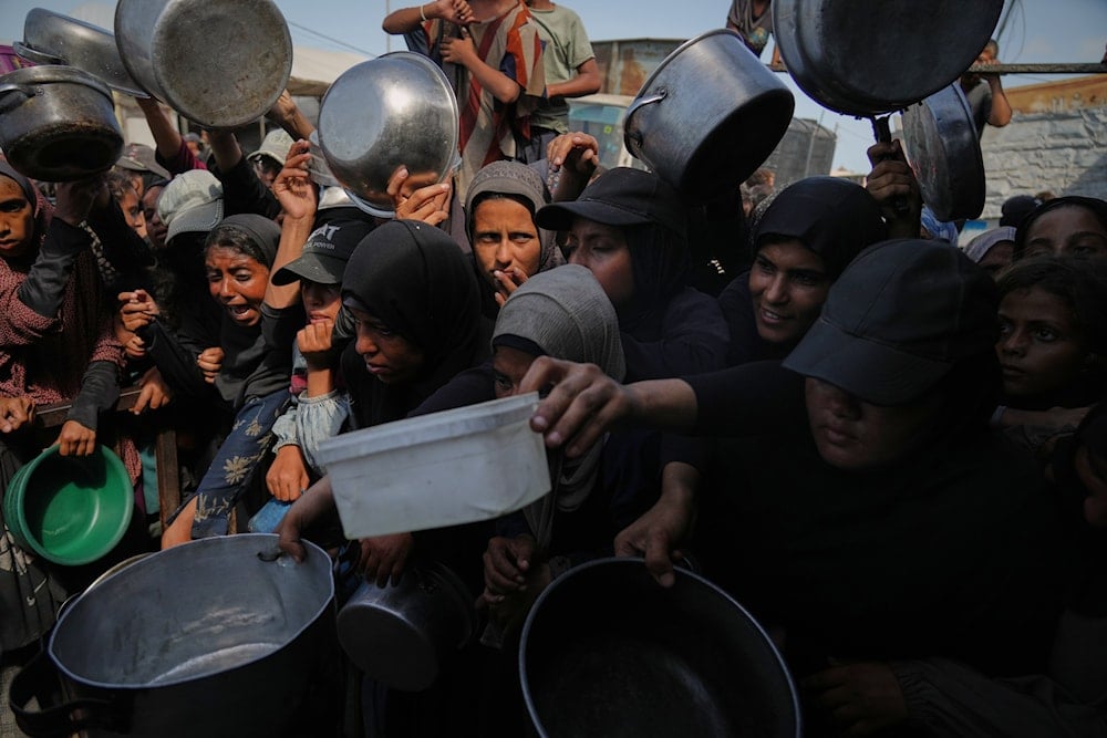 Palestinians struggle to get donated food at a community kitchen in Khan Younis, southern Gaza Strip, Sunday, Oct. 5, 2025 (AP)