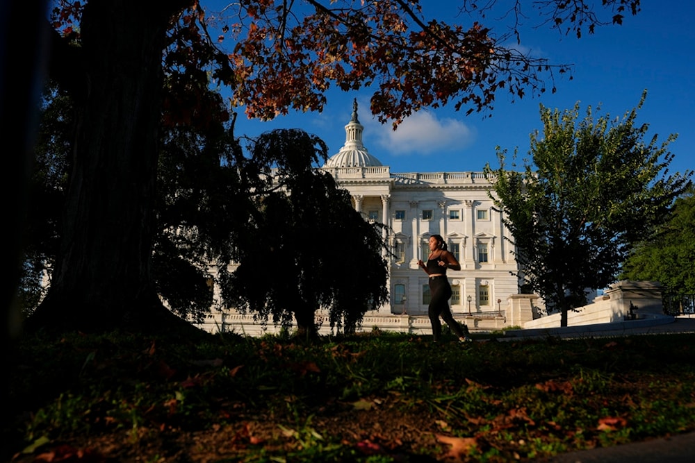 A person jogs past the US Capitol amid fall foliage, Tuesday, Oct. 14, 2025, in Washington. (AP Photo/Carolyn Kaster)