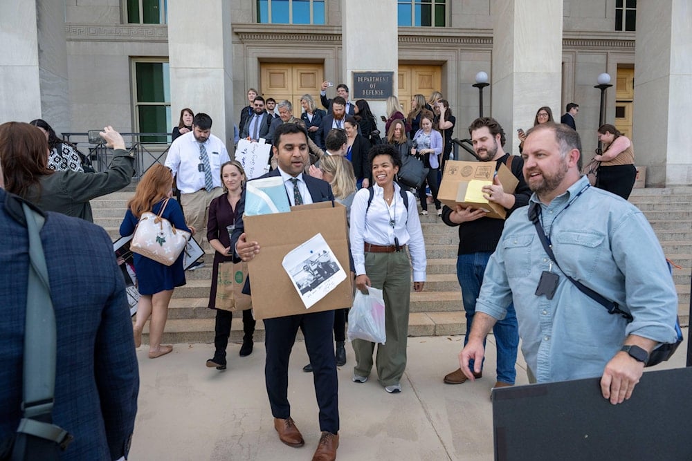 Members of the Pentagon press corp carry their belongings out of the Pentagon after turning in their press credentials, on October 15, 2025 in Washington. (AP Photo/Kevin Wolf)