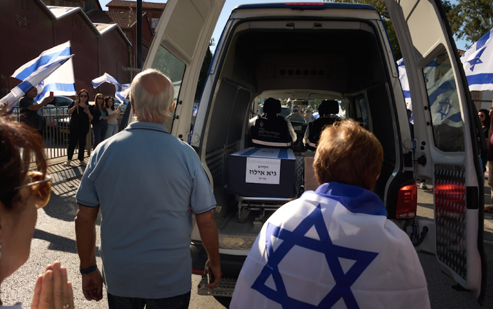 Mourners walk near the car carrying the coffin of a deceased Israeli captive in occupied Palesyine on October 15, 2025. (AP)