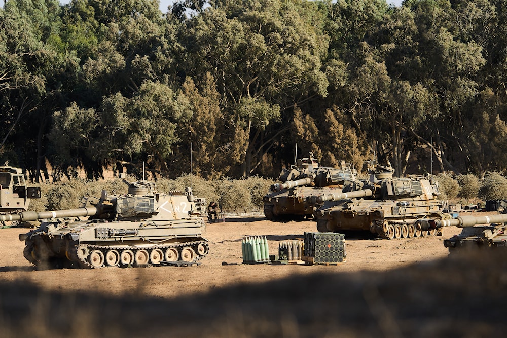 An Israeli soldier rests by a mobile artillery unit at a gathering point on the border with the Gaza Strip, in southern “Israel”, Saturday, Oct. 11, 2025. (AP)