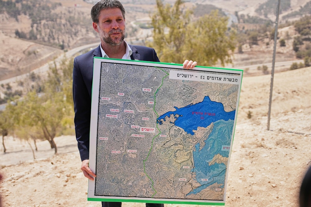 Israeli Finance Minister Bezalel Smotrich holds a map that shows the E1 settlement project during a press conference near the settlement of Maale Adumim, in the Israeli-occupied West Bank, Thursday, August 14, 2025. (AP Photo/Ohad Zwigenberg)