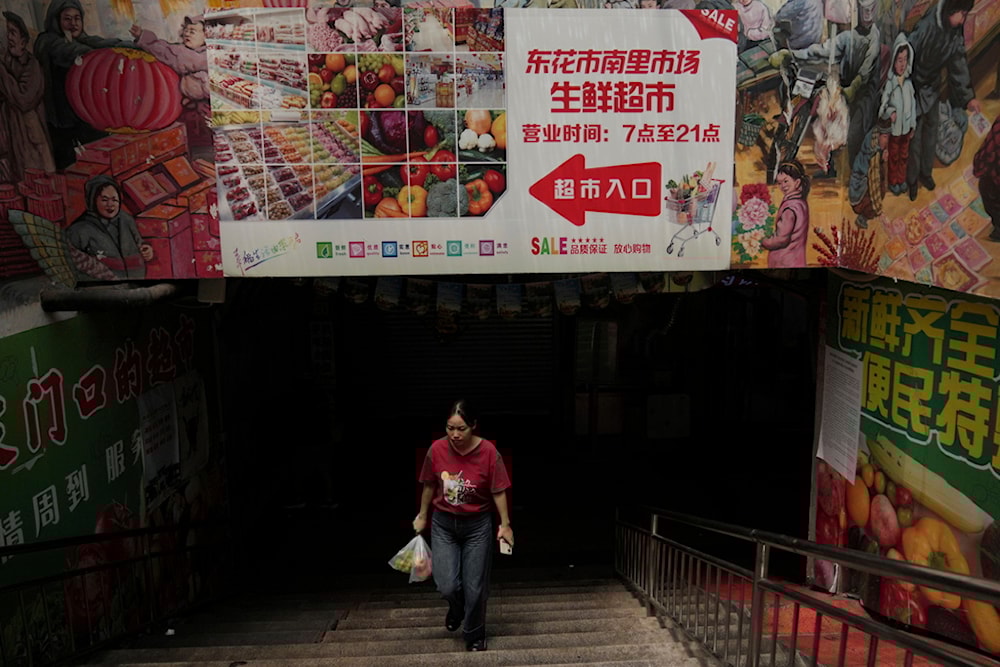 A woman with her purchased groceries walks out from an underground market, in Beijing, Wednesday, August 6, 2025. (AP Photo/Andy Wong)