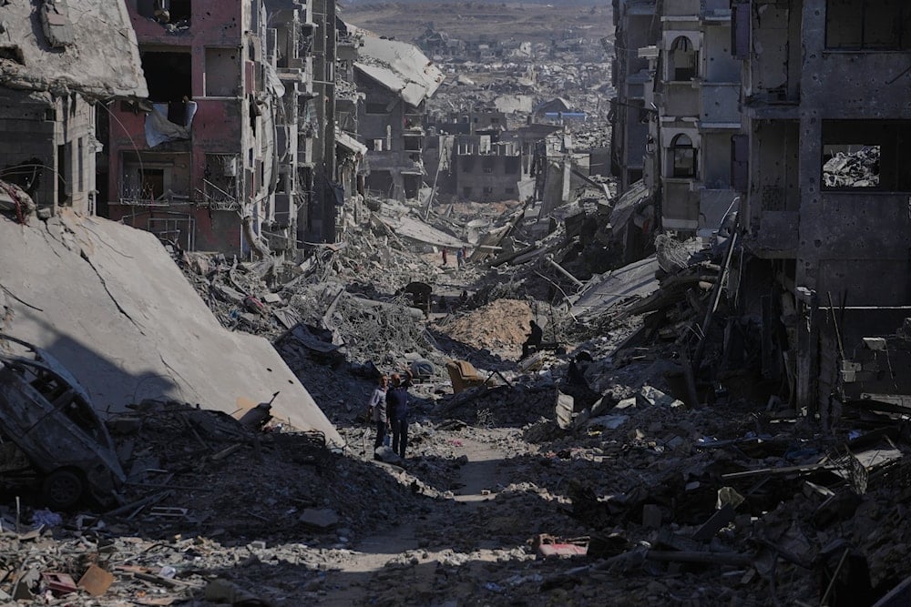 Palestinians walk among destroyed buildings in Gaza City, Thursday, Oct. 16, 2025 (AP)
