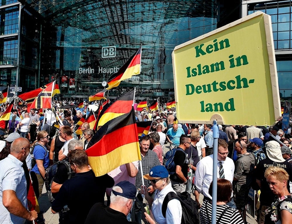 FILE - Supporters of the Alternative for Germany party wave flags in front of the train station in Berlin, May 27, 2018. The poster reads, 