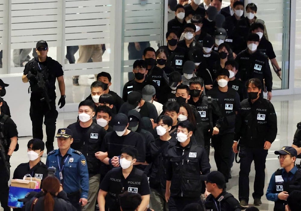 Police officers escort repatriated South Koreans, who were detained by authorities in Cambodia over alleged cyberscam operations, upon their arrival at Incheon International Airport, west of Seoul, on October 18, 2025. (Photo by YONHAP / AFP)