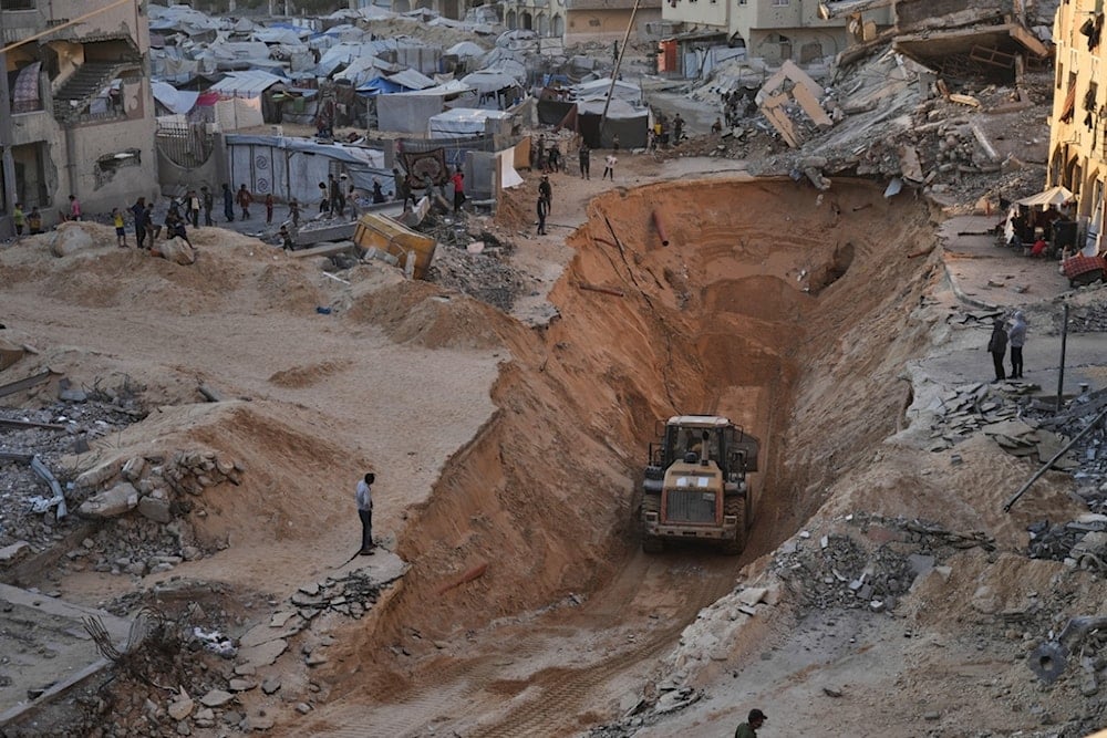 Palestinians watch Hamas fighters searching for bodies of the captives in Khan Younis, southern Gaza Strip, Saturday, October 18, 2025 (AP)