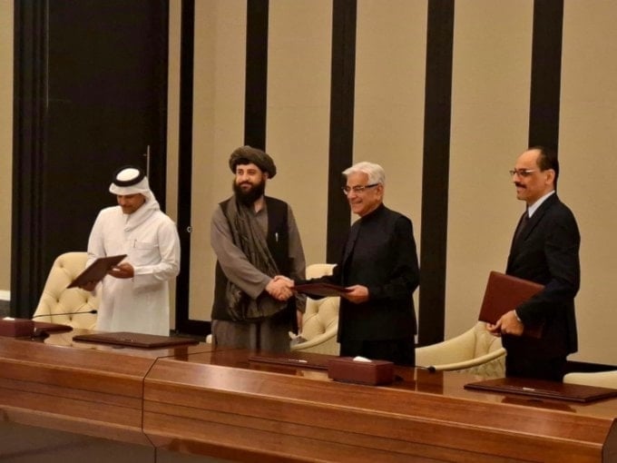 Photo of Afghanistan's Zabihullah Mujahid and Pakistani Defense Minister Khawaja Muhammad Asif shaking hands following the signing of a ceasefire deal on October 19, 2025 (X/@KhawajaMAsif)